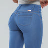 Close up of Latina woman wearing high-waisted blue butt lift jeans with 3D pockets and thick waistband.